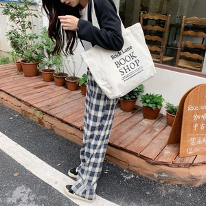 Detail of a large white canvas tote bag with black bookstore print in a street setting