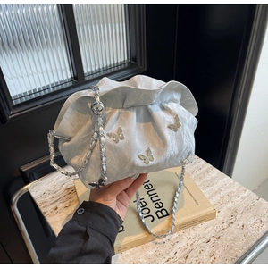 Detail of silver pleated cloud bag featuring 3D metallic butterfly accents and chain strap
