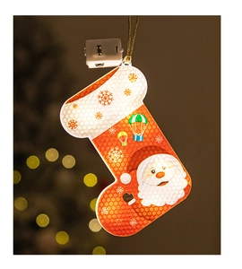 Detail of glowing Santa Claus Christmas stocking hanging light with warm LED bokeh