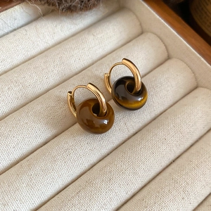 Close-up of vintage gold hoop earring with polished tiger eye stone bead detail