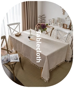 Close-up of beige linen tablecloth with white decorative tassels on rectangular table