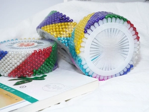 Macro shot of colorful round pearlized sewing pins in circular storage disc sets
