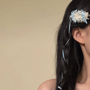 Gros plan sur une barrette en perles élégante avec ruban bleu sur les cheveux