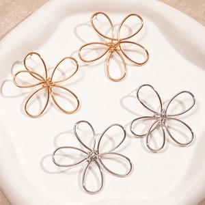 Minimalist hollow twisted flower earrings in gold and silver finish on white ceramic plate