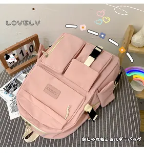 Detailed view of pink multi-pocket nylon backpack with utility buckles and brand label