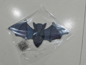 Detail of a black bat-shaped Halloween hanging ornament with a silver metal chain
