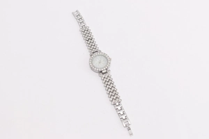 Close-up of a silver quartz watch with rhinestone flowers and a white numeral dial