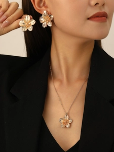 Detail of golden wrinkled texture flower earrings and necklace set worn by a model
