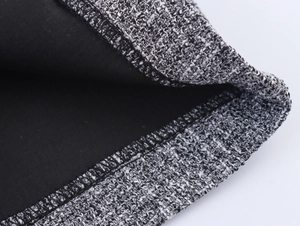 Detailed close-up of grey tweed fabric texture and hemwork on the two-piece suit