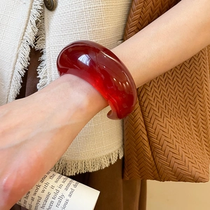 Detailed view of semi-transparent red resin cuff bracelet with polished finish and smooth curves
