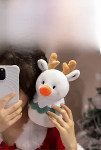 Detail of soft white plush reindeer toy with orange nose and cute green festive collar
