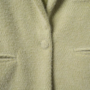 Macro detailopname van lichtgroene pluche jas met met stof beklede knopen en textuur