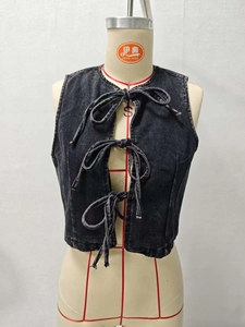 Detail of black washed denim vest featuring front lace-up bows and a round neckline