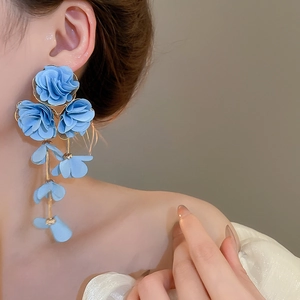 Detail of blue chiffon flower tassel earrings worn on ear with soft lighting