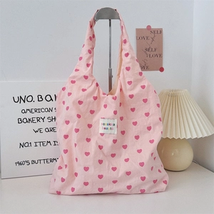 Detailed close-up of pink heart print canvas tote bag with woven brand label