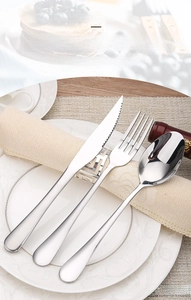 Detailed view of polished stainless steel cutlery set on a white ceramic dining plate