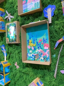 Artistic layered paper shadow boxes with forest animals on green faux moss background