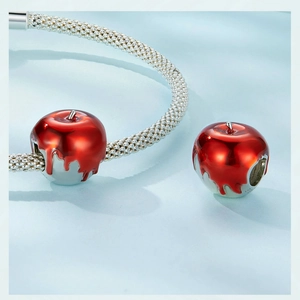 Macro view of a red enamel apple charm with melt design on silver mesh bracelet
