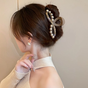 Pinza per capelli in acrilico marrone con perle e strass indossata su uno chignon