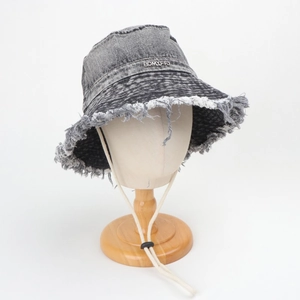 Dettaglio cappello alla pescatora in denim grigio scuro con bordi sfrangiati e laccetto