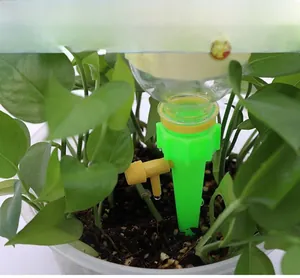 Adjustable green automatic plant watering spike inserted in soil with flow control valve