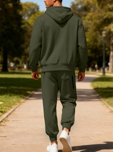 Uomo con tuta sportiva in pile verde oliva che cammina su un sentiero del parco