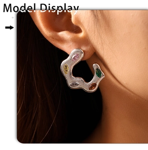 Detail view of model wearing silver C-shape earrings with colorful zircon stones