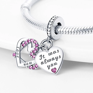 Macro detail of silver heart charm with pink gems and love you engraving on bracelet