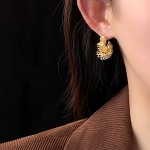 Close-up of a model wearing a gold twisted C-shape spiral earring with a modern design