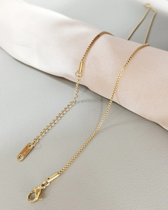 Detail of gold-plated stainless steel square link chain with lobster clasp on silk