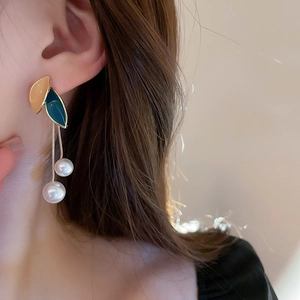 Macro view of vintage leaf earrings with enamel finish and hanging imitation pearls