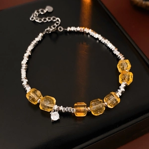 Macro shot of citrine beads and silver beads bracelet with heart charm on black leather