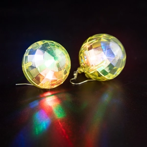 Macro shot of glowing yellow LED disco ball earrings with colorful light reflections