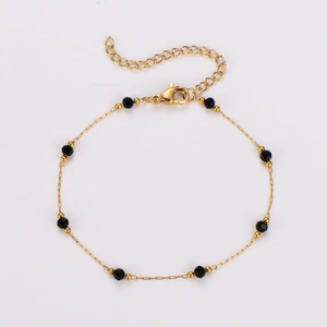 Détail de la chaîne en acier doré avec des perles noires facettées et fermoir mousqueton