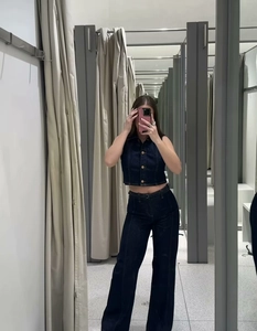 Détail de la coupe de la veste en jean sans manches et du pantalon large en bleu marine