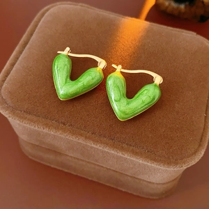 Detail of green enamel heart earrings with gold metal clasp on brown velvet box