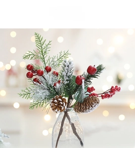 Detailed view of artificial cedar branches with red berries and snowy pine cones in a glass vase