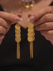 Détail de longues boucles d'oreilles dorées avec disques en métal brossé