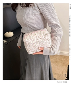 Close-up of quilted floral cotton cosmetic bag held by model featuring pink flower patterns