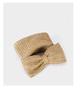 Close-up of beige woven straw clutch featuring a large bow detail and textured finish