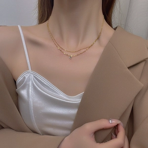 Elegant double layered gold necklace with round cubic zirconia pendant on model