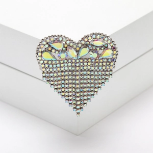 Detailed close-up of heart-shaped rhinestone brooch with tassel chain on white pedestal