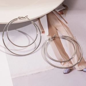 Close-up of geometric multi-layer silver circular hoops on a minimalist fashion background