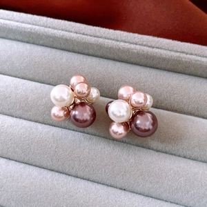 Detailed close-up of cluster pearl earrings with 18K gold plating on a velvet tray