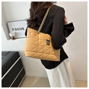 Detail of beige quilted shoulder bag with metal chain strap and turn-lock closure