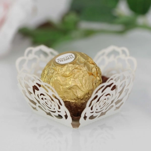 Detail of white laser-cut paper chocolate holder with elegant rose floral lace patterns