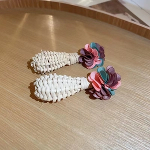 Macro detail of woven bohemian drop earrings with pastel fabric flowers on wood