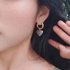 Boucles d'oreilles cœur bicolores or et argent portées par un mannequin en extérieur