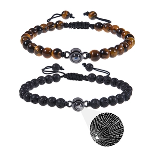 Detail of tiger eye and lava stone couple bracelets with I Love You projection charm