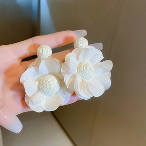Detailed macro view of white fabric flower earrings with elegant silk texture and pearl center